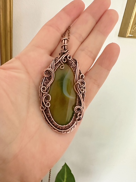 Artystyczny wisior z miedzi z pasami na kamieniu jako osobisty amulet na lancuszku.